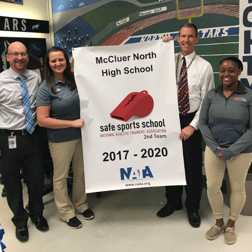  An image of athletics director Chris K., principal Dr. Croley, and 2 reps from NATA with banner.